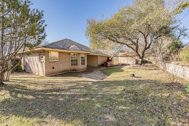 rear view of house with brick siding, a lawn, and fence