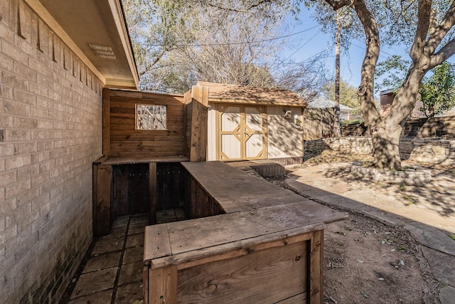 view of patio featuring a shed, fence, and an outbuilding