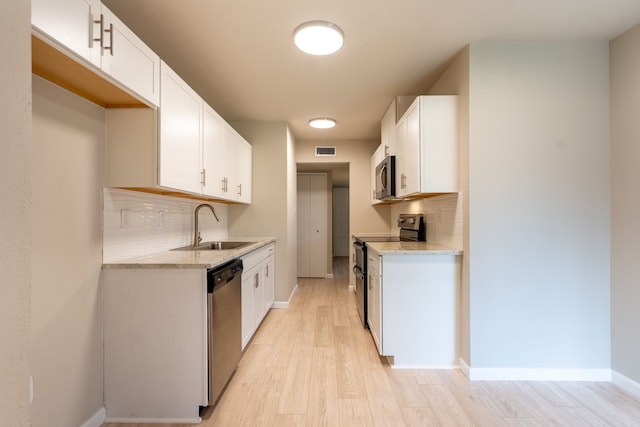 kitchen with light stone counters, visible vents, backsplash, appliances with stainless steel finishes, and a sink