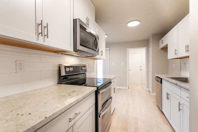 kitchen featuring stainless steel appliances, tasteful backsplash, white cabinetry, and light stone counters