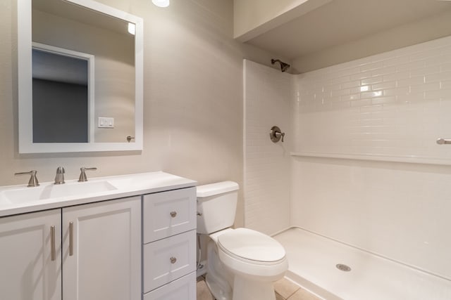 bathroom with toilet, a tile shower, and vanity