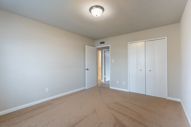 unfurnished bedroom with light carpet, baseboards, visible vents, and a closet