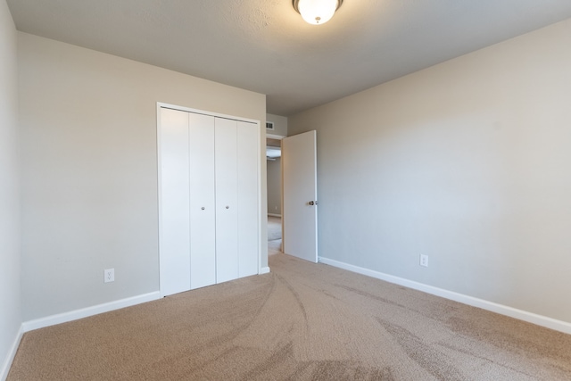 unfurnished bedroom with a closet, baseboards, and carpet flooring