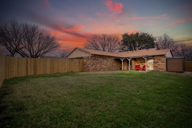 exterior space featuring a patio area, brick siding, a yard, and a fenced backyard