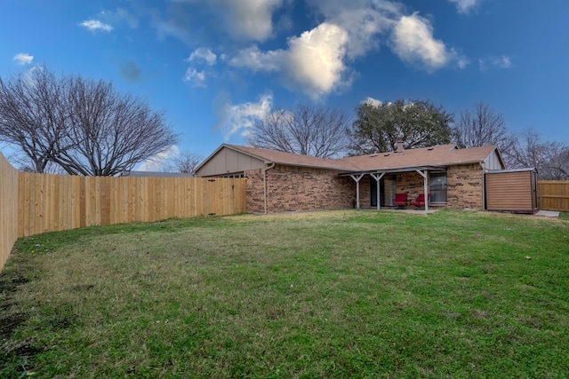 exterior space with a chimney, brick siding, a fenced backyard, and a front lawn