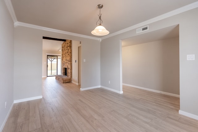 unfurnished room featuring light wood-type flooring, a brick fireplace, visible vents, and crown molding