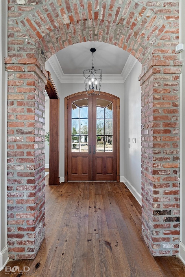 foyer entrance featuring hardwood / wood-style flooring, ornamental molding, and arched walkways