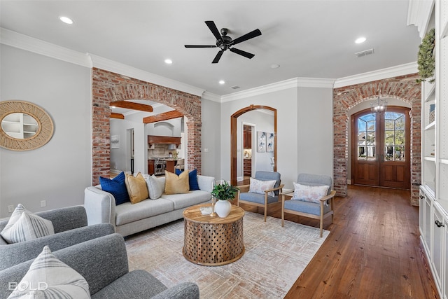 living area featuring arched walkways, recessed lighting, visible vents, wood-type flooring, and crown molding