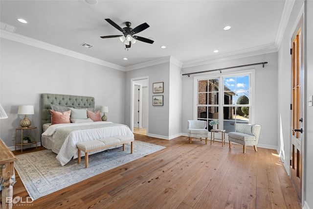 bedroom with ornamental molding, wood-type flooring, visible vents, and baseboards