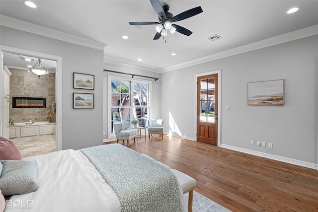 bedroom featuring ornamental molding, a tile fireplace, visible vents, and wood finished floors