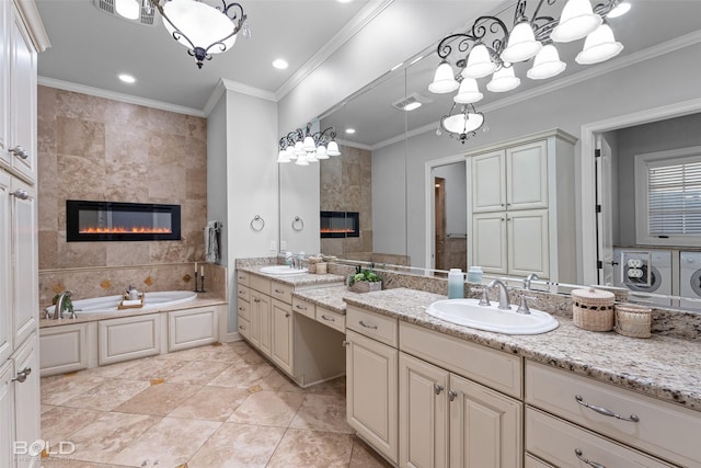 bathroom featuring ornamental molding, a sink, a tiled fireplace, and separate washer and dryer