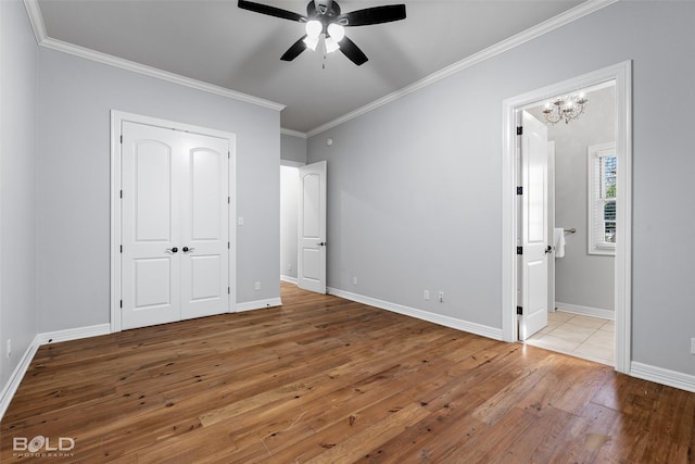 unfurnished bedroom featuring baseboards, hardwood / wood-style floors, ensuite bathroom, and crown molding