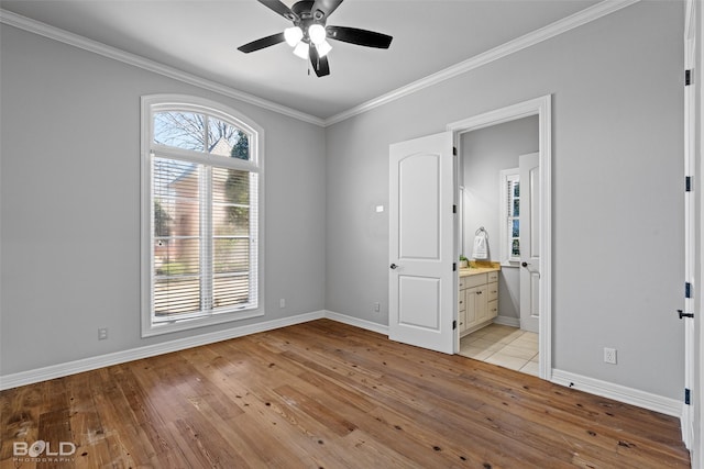 unfurnished bedroom with light wood-style floors, crown molding, and baseboards