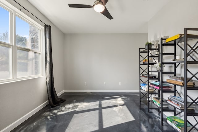 unfurnished room with ceiling fan, finished concrete flooring, and baseboards