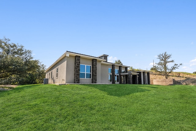 back of property featuring stucco siding, cooling unit, and a yard