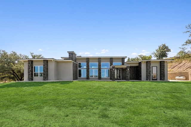 rear view of property featuring stone siding, a yard, and stucco siding