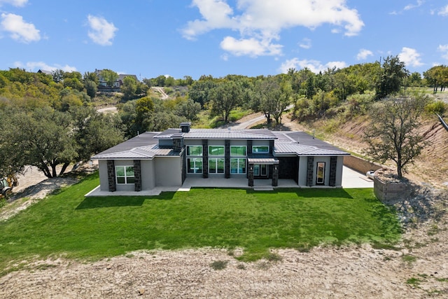 back of house with metal roof, a lawn, and a patio