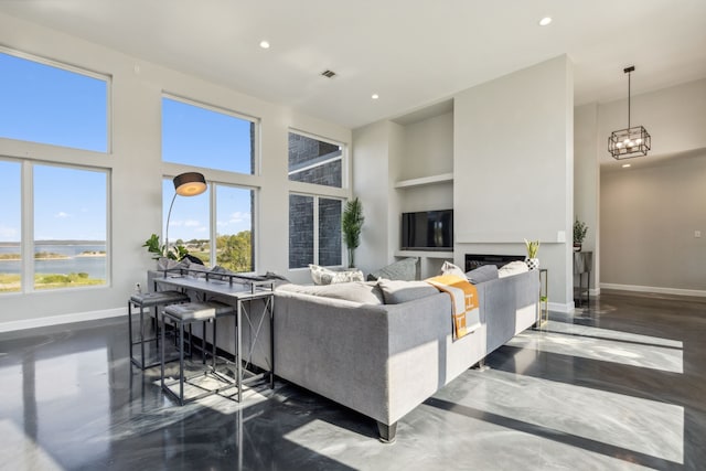 living area with a chandelier, built in shelves, recessed lighting, a towering ceiling, and baseboards