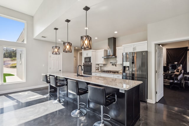 kitchen featuring white cabinets, an island with sink, wall chimney range hood, black appliances, and a sink