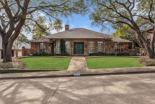 view of front of property with a chimney, a front lawn, and brick siding