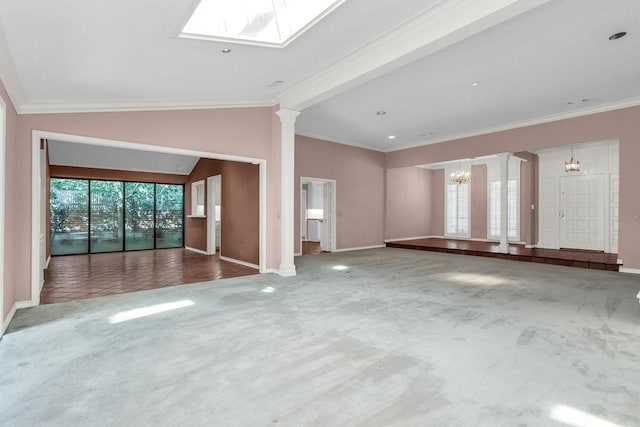 unfurnished living room featuring vaulted ceiling with skylight, ornamental molding, carpet, and a healthy amount of sunlight