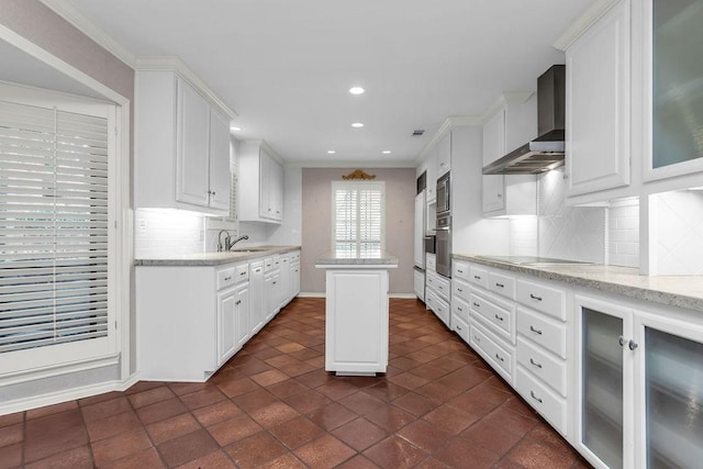 kitchen featuring wall chimney exhaust hood, stainless steel appliances, white cabinetry, a sink, and recessed lighting