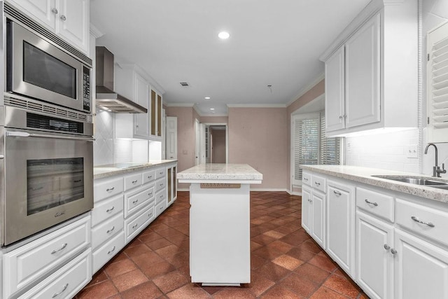 kitchen featuring decorative backsplash, appliances with stainless steel finishes, a sink, a kitchen island, and wall chimney exhaust hood