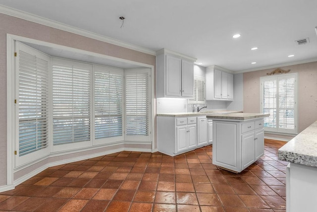 kitchen with white cabinets, light countertops, visible vents, and crown molding