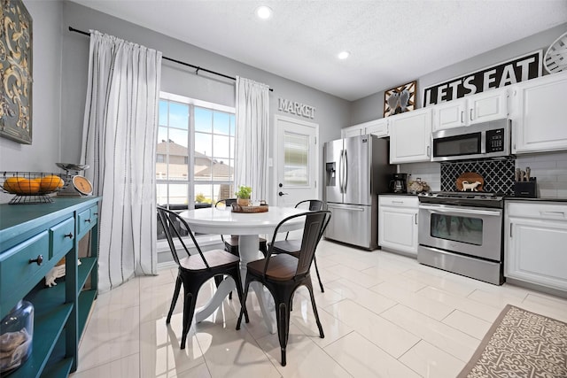 kitchen with appliances with stainless steel finishes, dark countertops, white cabinetry, and backsplash