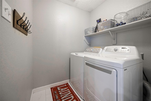 laundry area featuring marble finish floor, a textured ceiling, separate washer and dryer, laundry area, and baseboards