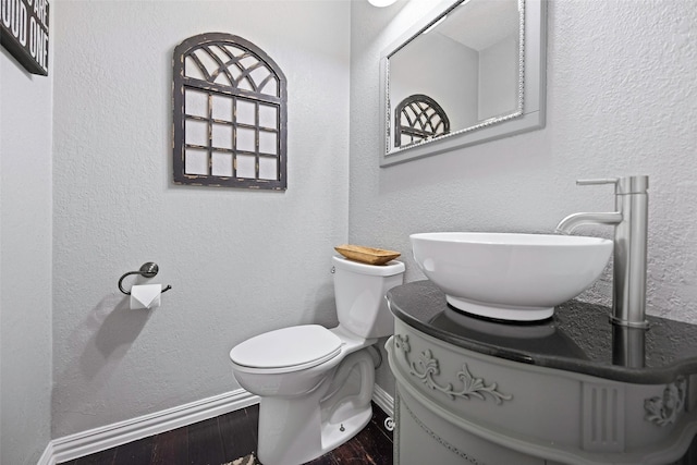 bathroom featuring baseboards, vanity, toilet, and wood finished floors