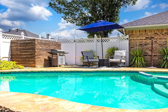 view of pool featuring a pool with connected hot tub, fence, and grilling area