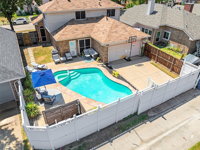 view of swimming pool featuring a patio, a pool with connected hot tub, a fenced backyard, and a gate