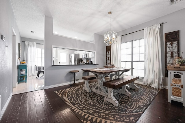 dining space with dark wood-style floors, a notable chandelier, baseboards, and a textured ceiling