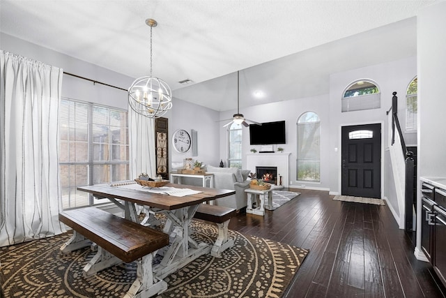 dining space with a warm lit fireplace, visible vents, a wealth of natural light, and dark wood-style flooring