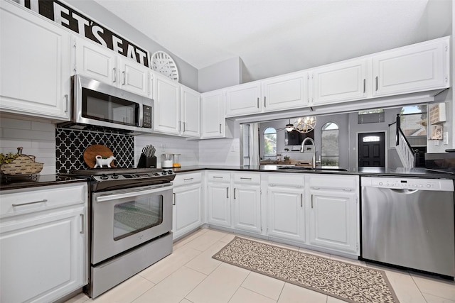 kitchen featuring a sink, white cabinetry, appliances with stainless steel finishes, tasteful backsplash, and dark countertops