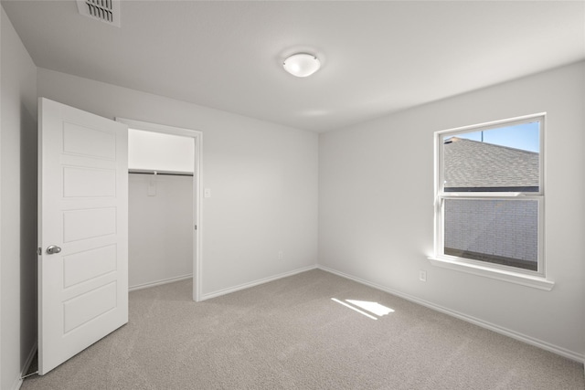 unfurnished bedroom with visible vents, baseboards, light colored carpet, and a closet