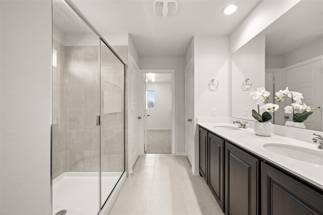 full bath with tile patterned flooring, visible vents, a shower stall, double vanity, and a sink