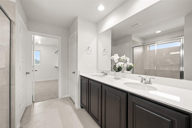 full bath with double vanity, a stall shower, tile patterned floors, and a sink