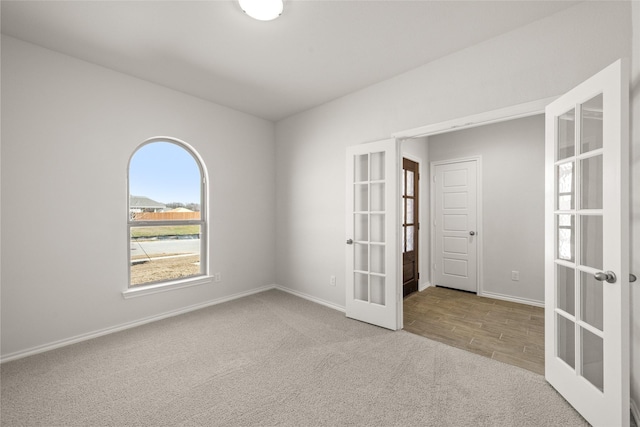 spare room with french doors, carpet, baseboards, and wood finished floors