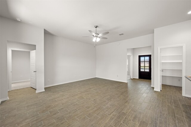 unfurnished living room featuring a ceiling fan, wood finished floors, visible vents, and baseboards