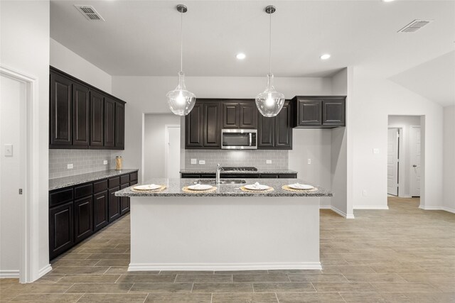 kitchen with stainless steel microwave, visible vents, and wood tiled floor