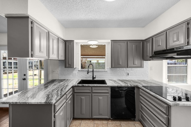 kitchen with gray cabinetry, a sink, a peninsula, under cabinet range hood, and black appliances