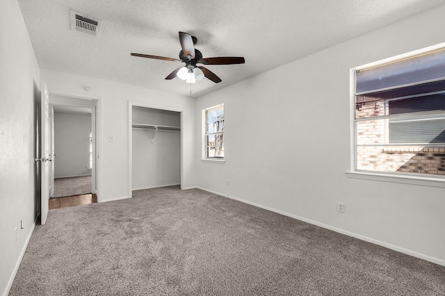 unfurnished bedroom with carpet floors, a closet, visible vents, a textured ceiling, and baseboards