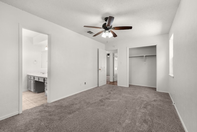 unfurnished bedroom featuring a closet, visible vents, light carpet, connected bathroom, and a textured ceiling