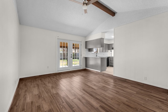 unfurnished living room with a ceiling fan, lofted ceiling with beams, dark wood-type flooring, a textured ceiling, and french doors