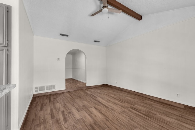 spare room with lofted ceiling with beams, visible vents, arched walkways, and wood finished floors