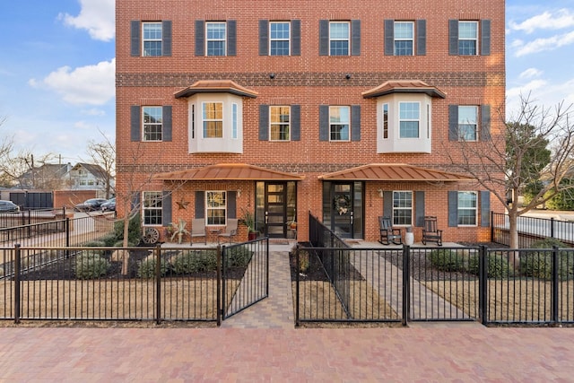 multi unit property featuring a fenced front yard, a patio area, and brick siding