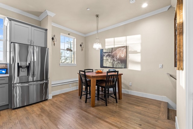 dining space with an inviting chandelier, baseboards, ornamental molding, and wood finished floors