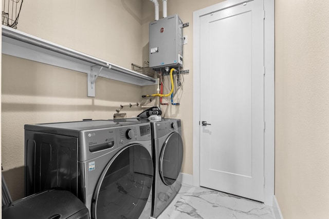 laundry room featuring marble finish floor, washer and clothes dryer, tankless water heater, laundry area, and baseboards